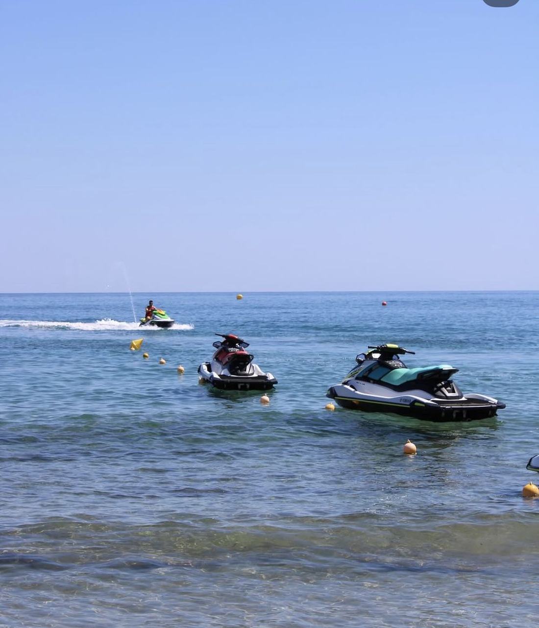 Jet skis waiting in the shallow water in front of the beach